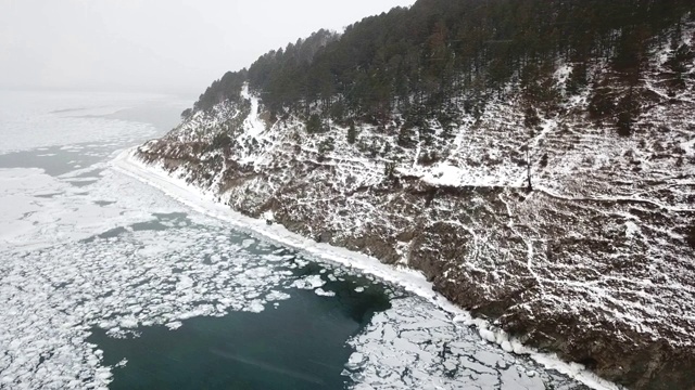 空中透视美丽的深蓝冰纹理冻结贝加尔湖表面和海岸从上面拍摄的无人机在晴朗的冬日在俄罗斯视频素材