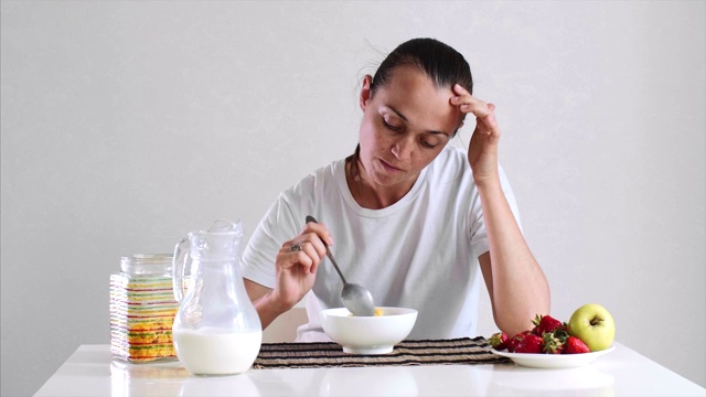 年轻女子正在吃玉米片加牛奶和水果的早餐。视频素材