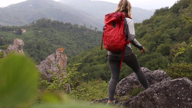 女性徒步旅行者到达山谷上方的岩石露头视频素材