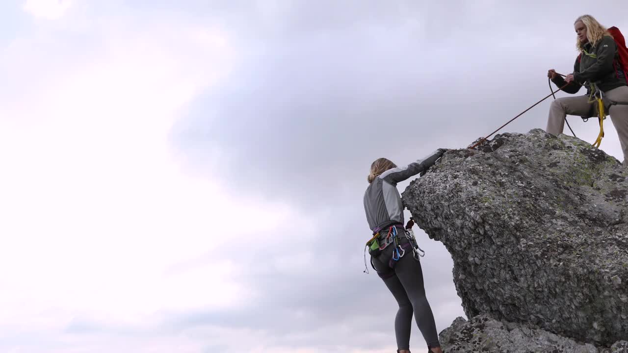 女登山者攀登山谷、山脉上的岩石山脊视频素材