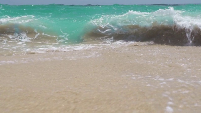 蓝绿色的海浪拍打在沙滩上蓝色的天际线景观。在地平线背景上，海浪拍打着沙滩。海上冲浪的背景视频素材