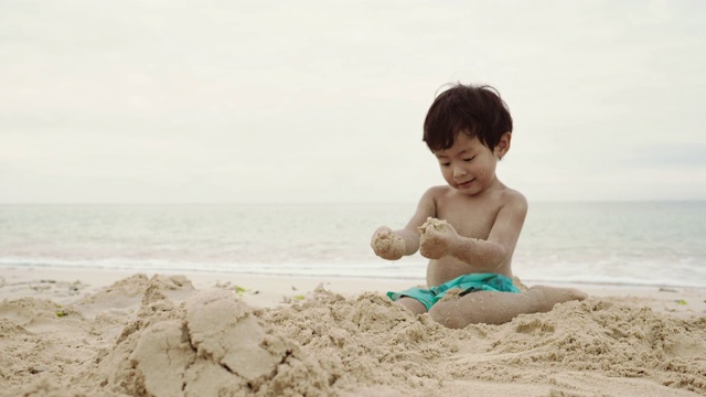 小男孩喜欢在海边玩沙子视频素材