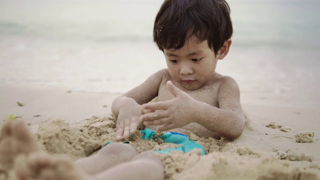 小男孩喜欢在海边玩沙子视频素材