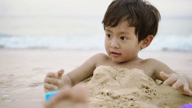 小男孩喜欢在海边玩沙子视频素材