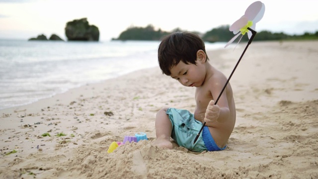 小男孩喜欢在海边玩沙子视频素材