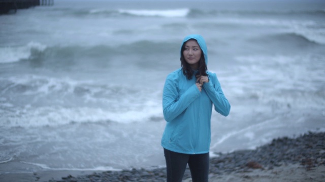 一名年轻女子在暴风雨中站在海滩上视频素材