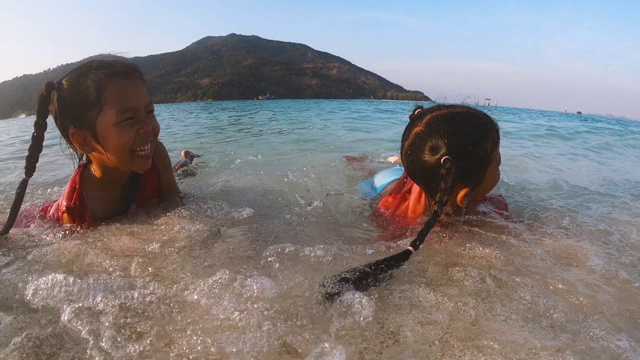 亚洲女孩躺在沙滩上享受海浪带来的乐趣视频素材