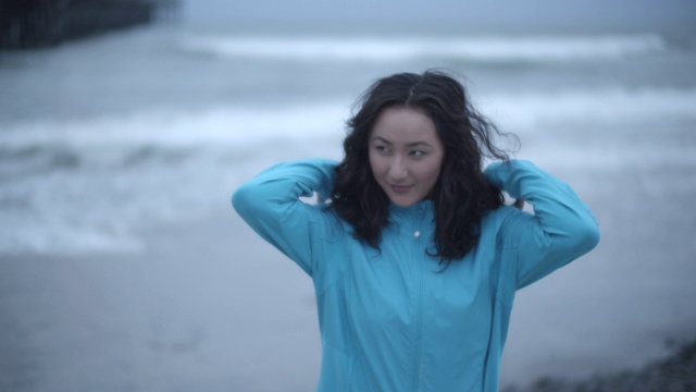 一名年轻女子在暴风雨中走在海滩上视频素材