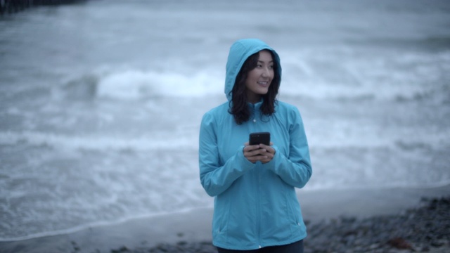 一名年轻女子在暴风雨中走在海滩上视频素材