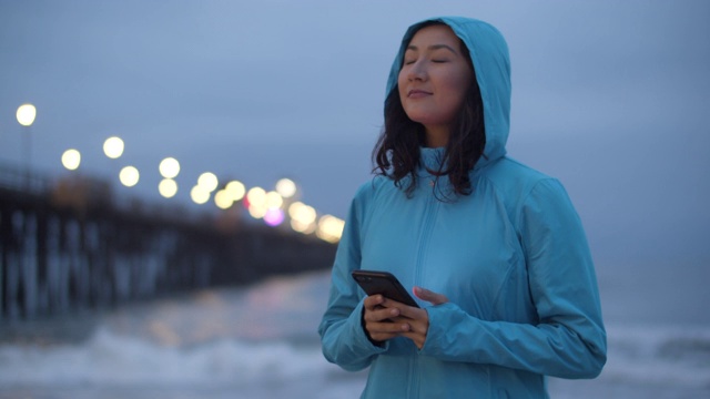 一个年轻女子在海滩上走着发短信视频素材