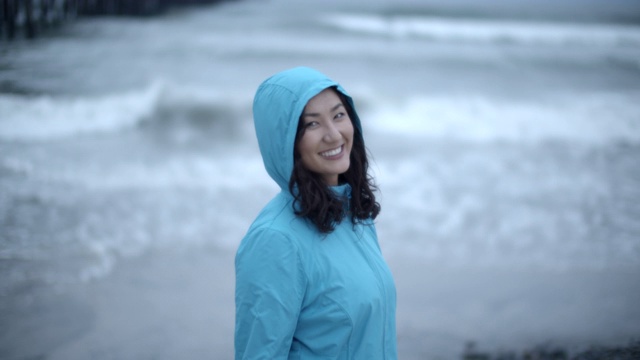 一名年轻女子在暴风雨中走在海滩上视频素材