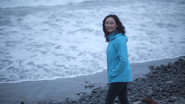 一名年轻女子在暴风雨中看着海浪视频素材