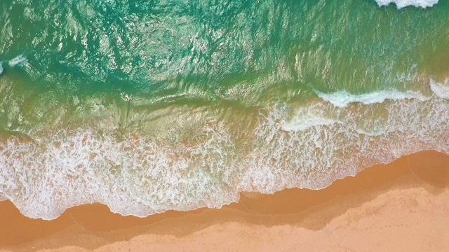 鸟瞰图。浪花在白色的沙滩上拍打。海浪拍打着美丽的海滩视频素材