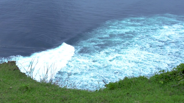 从绿色的山边看，浪花和白色的泡沫在海面上。海浪溅。水青绿色背景视频素材