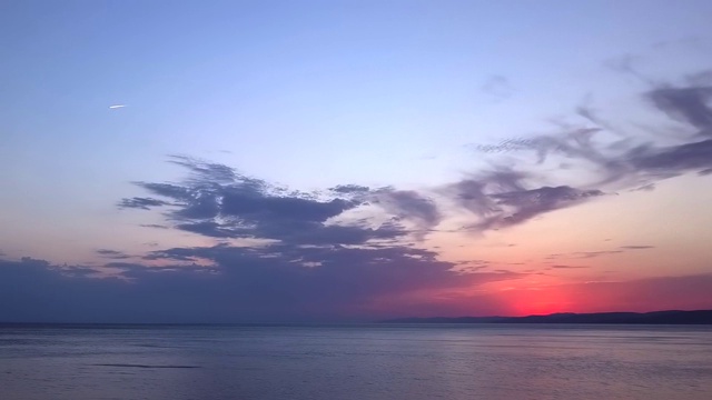 飞机在日落的天空中飞越大海视频素材