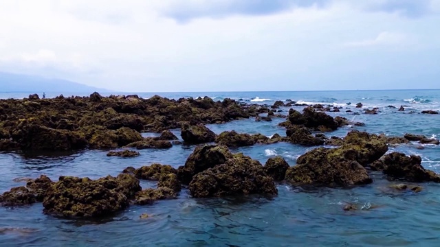 钓鱼海滩摄像机运动的观点与广阔的岩石珊瑚礁在村庄视频素材