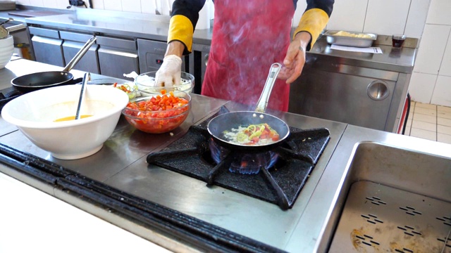 面目全非的厨师为餐厅游客烹制美味的素食菜肴。男厨师在煤气炉上的热锅里扔食材。浅谈餐厅厨房的烹饪过程。慢动作视频素材