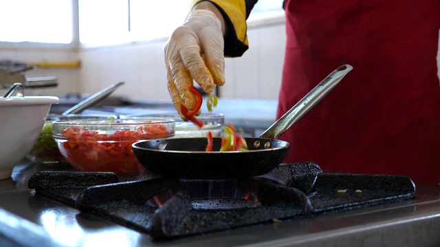 面目全非的厨师为餐厅游客烹制美味的素食菜肴。男厨师在煤气炉上的热锅里扔食材。浅谈餐厅厨房的烹饪过程。底视图Slowmo视频素材