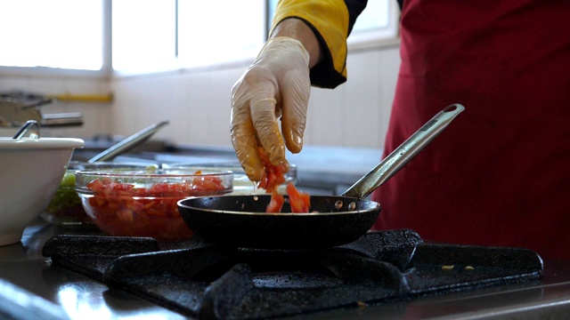 面目全非的厨师为餐厅游客烹制美味的素食菜肴。男厨师在煤气炉上的热锅里扔食材。浅谈餐厅厨房的烹饪过程。底视图Slowmo视频素材