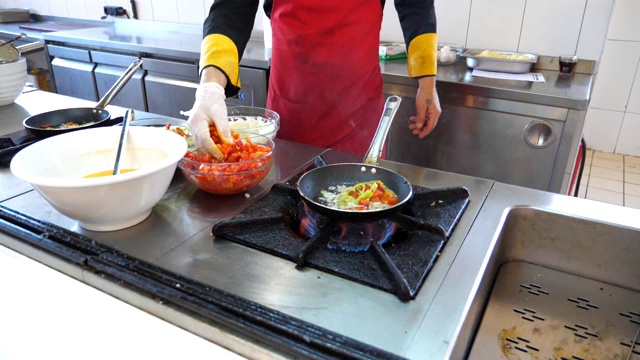 面目全非的厨师为餐厅游客烹制美味的素食菜肴。男厨师在煤气炉上的热锅里扔食材。浅谈餐厅厨房的烹饪过程。慢动作视频素材