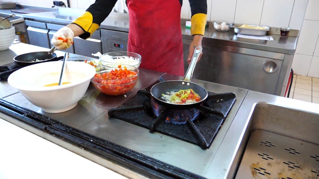 面目全非的厨师为餐厅游客烹制美味的素食菜肴。男厨师在煤气炉上的热锅里扔食材。浅谈餐厅厨房的烹饪过程。慢动作视频素材