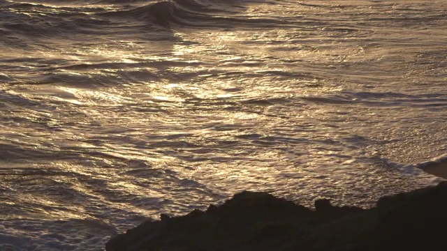 夕阳西下，浪花轻轻拍打着海滩视频素材