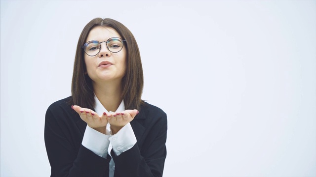 年轻迷人的微笑女商人在黑色西装站，给一个飞吻，摆姿势，微笑幸福。视频素材