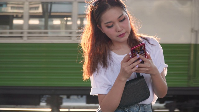 漂亮的年轻女子在火车站使用手机视频素材