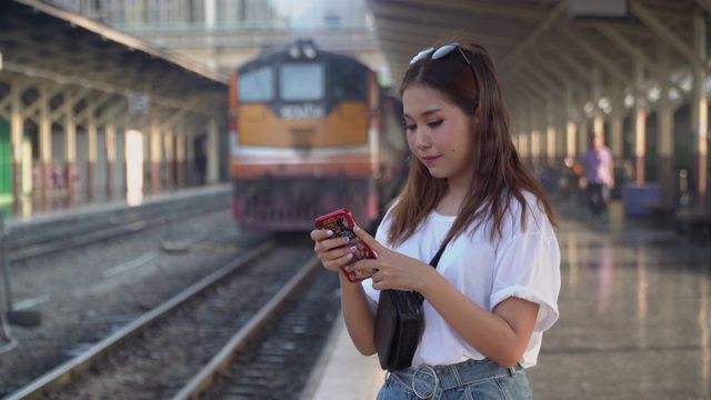 年轻女性游客在火车站使用手机视频素材