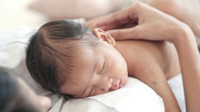 亚洲男婴睡在漂亮的妈妈身上。母亲节概念。视频素材