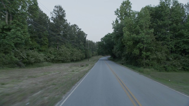 加工板直背农村地区或乡村道路两旁的树木。有些房子部分可见。视频素材