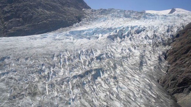 空中盘旋:雪覆盖，纹理，岩石地面灰色山脉-门登霍尔冰川，阿拉斯加视频素材