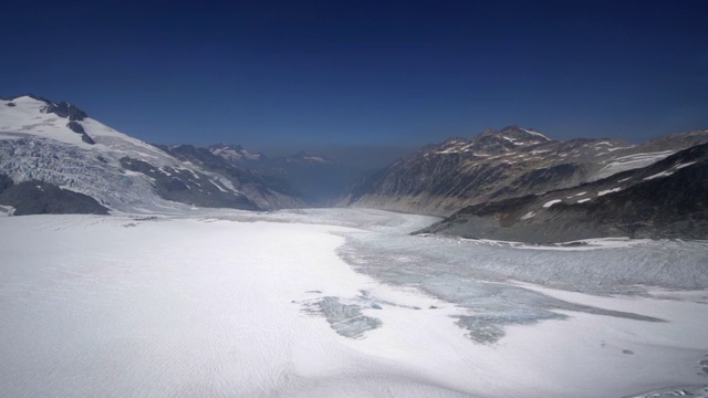 空中右图:被群山包围的雪谷，多雾，上方是蓝天——门登霍尔冰川，阿拉斯加视频素材