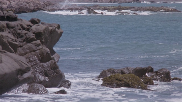 海岸上的岩石和海浪冲击防波堤的中等角度。视频素材