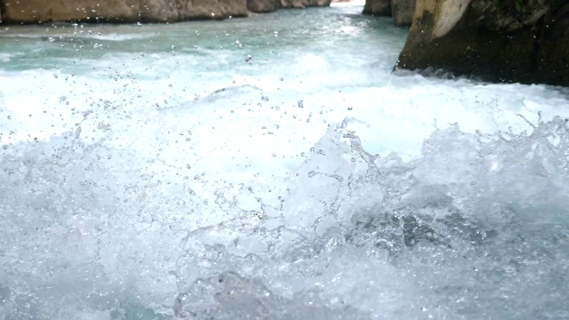 快速流动的山河溪流的观点。强大的洪水冲击石质表面，溅起晶莹剔透的水。Сool在岩石地形中流淌的清爽小溪。慢镜头视频素材