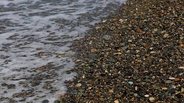 海浪在卵石滩上冲浪，暑假在海边。视频素材