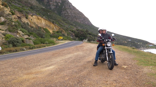 一对退休夫妇在沿海公路上一起骑摩托车旅行。视频素材