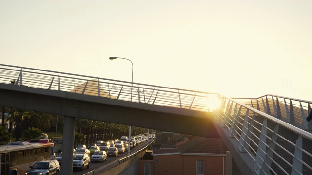 黄昏时分，一对情侣在横跨城市交通的桥上慢跑视频素材