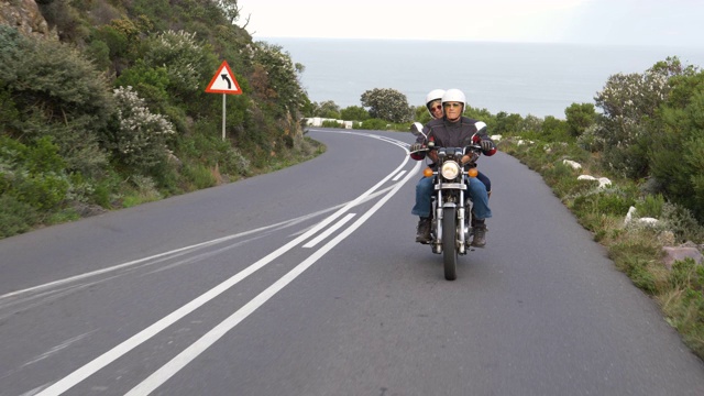 一对退休夫妇在沿海公路上一起骑摩托车旅行。视频素材