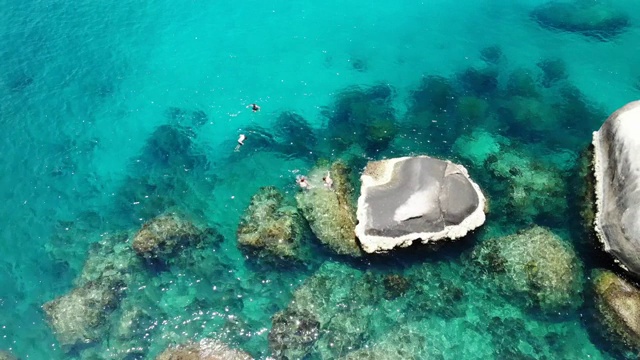 石头附近有平静的海水。在泰国阳光明媚的日子里，宁静的蓝色海水和灰色的巨石是潜水的完美场所。自然背景纹理。视频素材