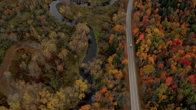 空中盘旋:汽车驾驶在道路上通过色彩鲜艳，森林覆盖平原-迪克斯维尔Notch，新罕布什尔州视频素材