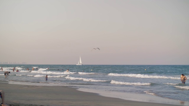 海景，沐浴的人们和白色的帆船视频素材