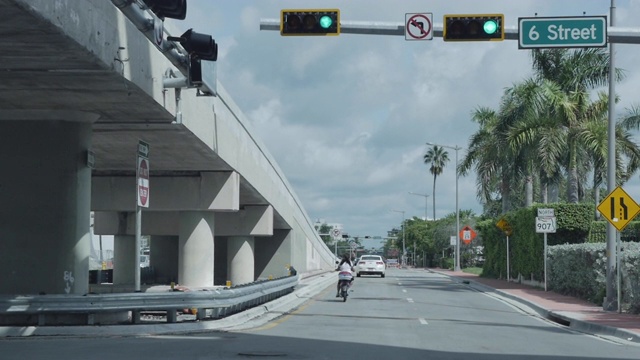 迈阿密道路交通与多云的天空在6街。摩托车和汽车。路标，棕榈树。视频素材