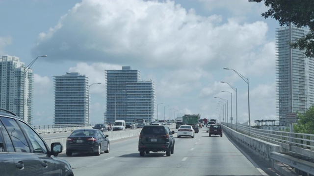 通往迈阿密海滩的美国高速公路上的路标。北，海滩，装饰艺术历史区，奥尔顿路。这天是多云的蓝天。缓慢的运动。RoadSign。棕榈树。交通车辆和摩天大楼。视频素材