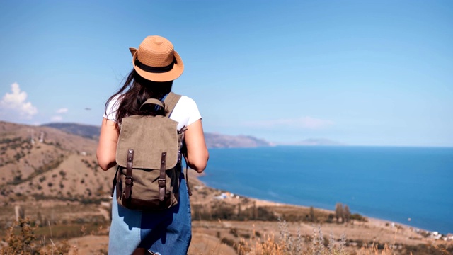 后视图活跃的背包女欣赏美丽的海景接近山顶视频素材