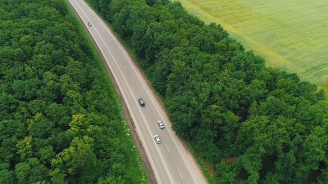 田野间道路的鸟瞰图。夏天的颜色。空中的绿色乡村和汽车通过。4 k。视频素材