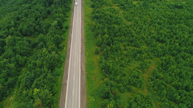 田野间道路的鸟瞰图。夏天的颜色。空中的绿色乡村和汽车通过。4 k。视频素材