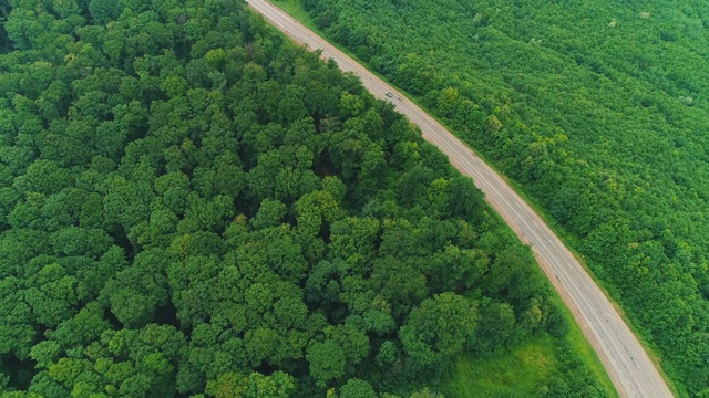 空中飞过的汽车沿着被森林包围的道路行驶。4 k。视频素材