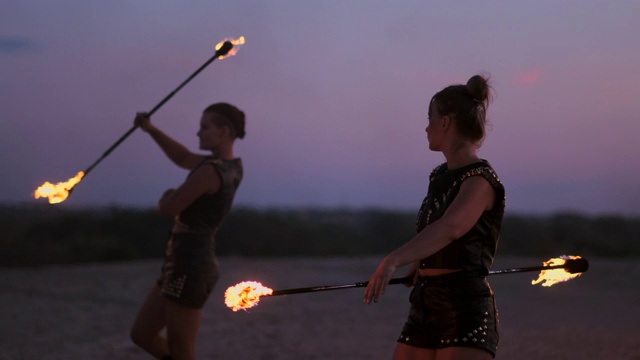 日落时，在沙滩上，手持火种的女子在美丽的天空的映衬下，慢动作地舞蹈表演。视频素材