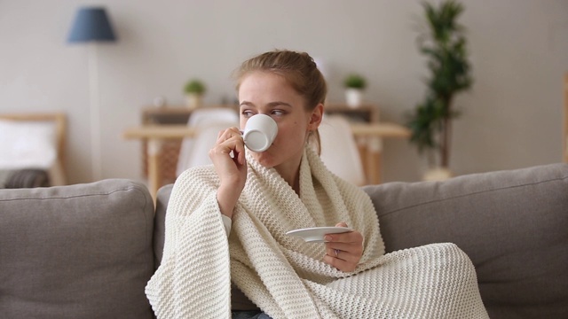 梦幻快乐的女孩坐在沙发盖格子喝咖啡视频素材